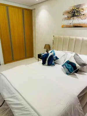 a large white bed with blue pillows on it at Plush & Modern 2BR Luxury stay with picturesque Rooftop 64th floor in Dubai