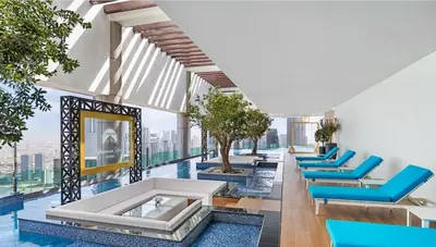 a hotel lobby with blue chairs and a pool at Plush & Modern 2BR Luxury stay with picturesque Rooftop 64th floor in Dubai