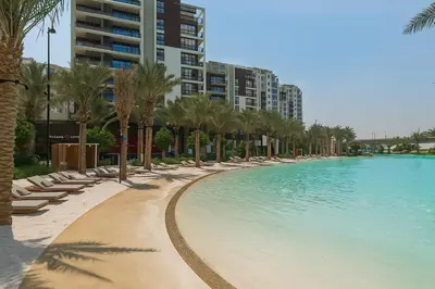 a swimming pool with lounge chairs and palm trees at Apartment In Creek Beach in Dubai