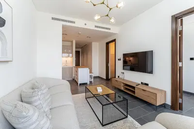 a living room with a couch and a tv at HAVN - 2 Bedroom Luxe Stay at The Crest, Sobha in Dubai