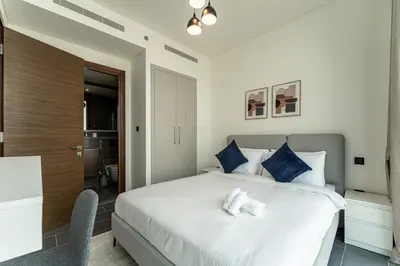a bedroom with a large white bed with blue pillows at HAVN - 2 Bedroom Luxe Stay at The Crest, Sobha in Dubai