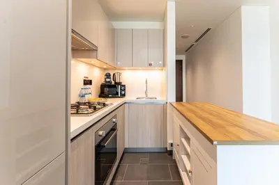 a kitchen with white cabinets and a wooden counter top at HAVN - 2 Bedroom Luxe Stay at The Crest, Sobha in Dubai