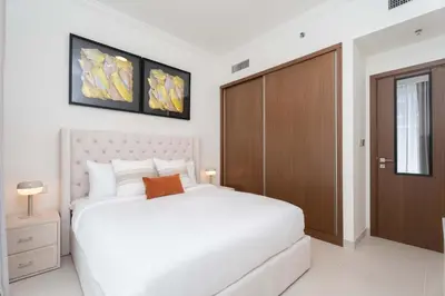 a bedroom with a white bed and a wooden door at Luxury 1 Bedroom in Emaar Beach Front - Dubai Marina - Private Beach in Dubai