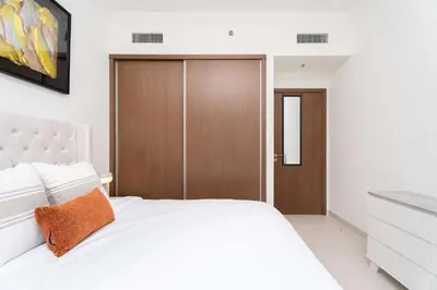 a bedroom with a white bed and a wooden door at Luxury 1 Bedroom in Emaar Beach Front - Dubai Marina - Private Beach in Dubai