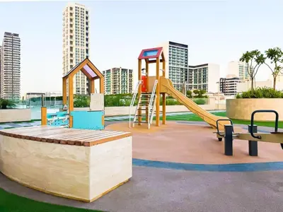 a playground with a slide and a bench and buildings at Luxury 1BR in Binghatti Onyx JVC with Pool, Gym & Balcony in Dubai