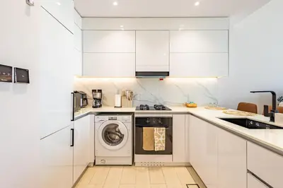 a white kitchen with a washing machine in it at Luxury 1BR in Binghatti Onyx JVC with Pool, Gym & Balcony in Dubai