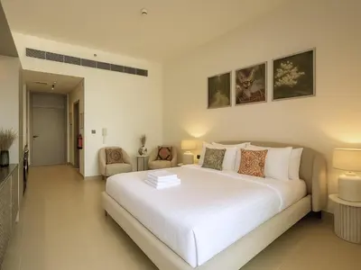 a bedroom with a large white bed and two chairs at Stylish Studio 10 Mins from Dubai Mall Meydan Area in Dubai