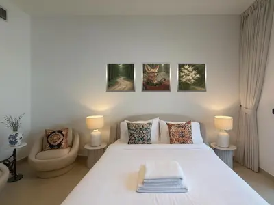 a white bedroom with a bed and a chair at Stylish Studio 10 Mins from Dubai Mall Meydan Area in Dubai