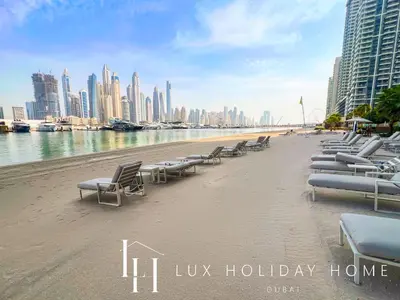 a row of chaise lounges on a beach near the water at LUX The Palace Residence Suite 2 in Dubai