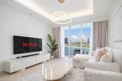 a white living room with a tv and a couch at LUX The Palace Residence Suite 2 in Dubai