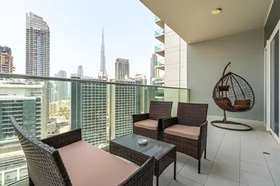 a balcony with chairs and tables and a view of the city at Luxury 2 Bed with Iconic Burj View, Near Dubai Mall in Dubai