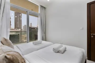 two white beds in a room with a large window at Luxury 2 Bed with Iconic Burj View, Near Dubai Mall in Dubai
