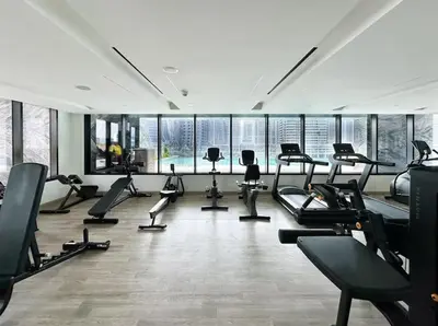 a gym with treadmills and ellipticals in a room with windows at Water Dream with Burj Views Sleeps 4 in Dubai