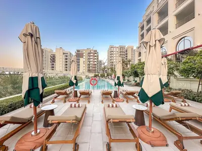 a swimming pool with lounge chairs and umbrellas at FIRST CLAS 1BR Creek Beach , Lagoon Access in Dubai