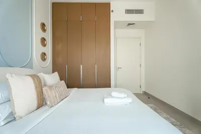 a bedroom with a large white bed with wooden cabinets at GuestReady - Canal View | 3 Bed | Lagoon Stay in Dubai