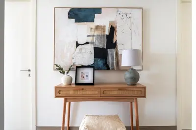 a console table with a lamp and a painting on the wall at GuestReady - Canal View | 3 Bed | Lagoon Stay in Dubai