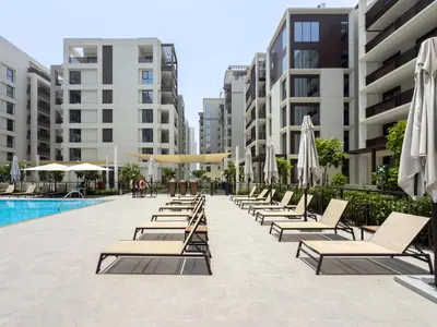 a row of chairs and umbrellas next to a pool at GuestReady - Canal View | 3 Bed | Lagoon Stay in Dubai