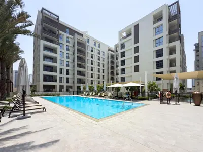 a swimming pool with chairs and umbrellas and buildings at GuestReady - Canal View | 3 Bed | Lagoon Stay in Dubai