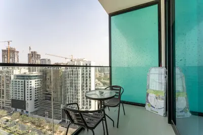 a balcony with a table and chairs and a window at HAVN - Bright & Cozy Studio at Binghatti Azure JVC in Dubai