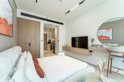 a living room with a white couch and a television at HAVN - Bright & Cozy Studio at Binghatti Azure JVC in Dubai