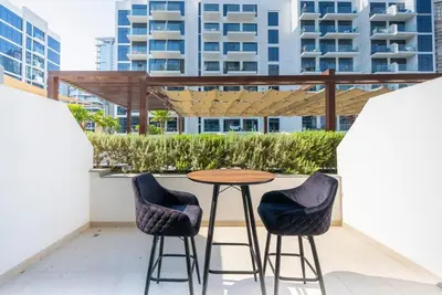 a patio with a table and two stools at Cozy Studio with a huge terrace in Dubai
