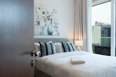 a bedroom with a bed with pillows and a window at Reva 1BR - Downtown Living with Burj Khalifa View in Dubai