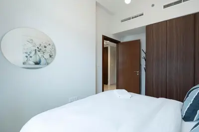 a bedroom with a white bed and a clock on the wall at Reva 1BR - Downtown Living with Burj Khalifa View in Dubai