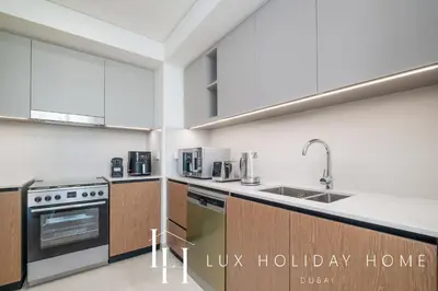 a kitchen with white walls and wooden cabinets at LUX The Creek Palace Residence Suite 2 in Dubai