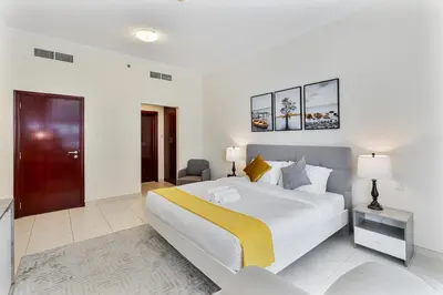 a white bedroom with a large bed and a chair at Bright 1BR with Canal Views Near Burj Khalifa in Dubai