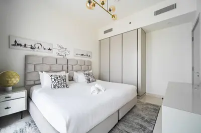 a white bedroom with a large bed with white sheets at SettlerHomes - Sunrise Beach Bliss With Private Beach in Dubai