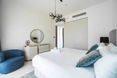 a bedroom with a white bed and a blue chair at SettlerHomes - Sunrise Beach Bliss With Private Beach in Dubai