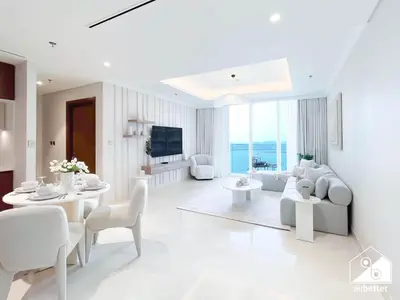 a living room with white furniture and a television at Beachfront 1B at Palm Jumeirah with Balcony & Views in Dubai