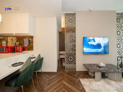 a kitchen with a table and a tv on a wall at Le Chateau Vacation Homes,Fashion Avenue Residence in Dubai