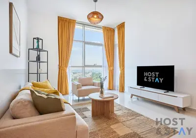 a living room with a couch and a tv at Radiant & Sunny Living - 1BR in ORchid DAMAC Hills in Dubai