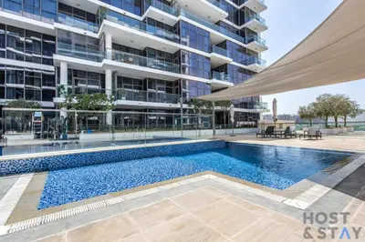 a swimming pool in front of a building at Radiant & Sunny Living - 1BR in ORchid DAMAC Hills in Dubai