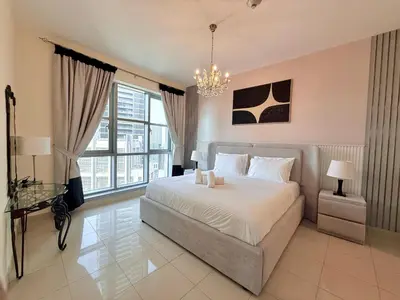 a bedroom with a large bed and a chandelier at Urban Retreat 1BR with Pool & Burj Glimpse in Dubai