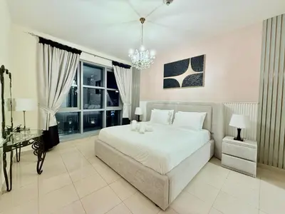 a bedroom with a large bed and a chandelier at Urban Retreat 1BR with Pool & Burj Glimpse in Dubai
