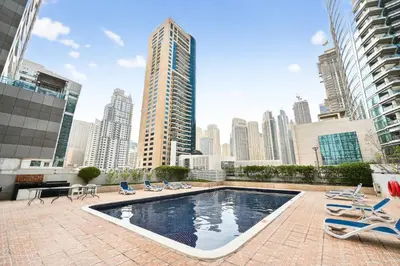 a swimming pool with lounge chairs and a city skyline at Luxury 2BR Marina View-walking distance to JBR beach, marina mall & metro in Dubai