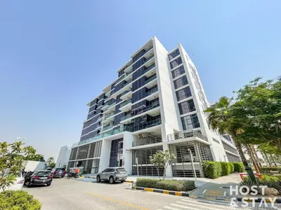 a tall building with cars parked in a parking lot at Modern Studio in Loreto 1A, Damac Hills in Dubai
