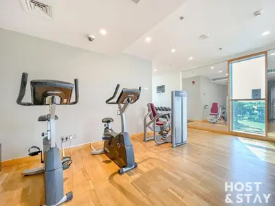 a gym with treadmills and exercise bikes in a room at Modern Studio in Loreto 1A, Damac Hills in Dubai