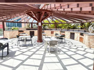 a patio with tables and chairs under a wooden umbrella at Luxuries Sky View Apartment in Dubai