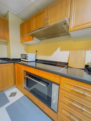 a kitchen with wooden cabinets and a stove top oven at Walk to JBR Marina Beach & Tram! Luxury Family 3BD, Stunning Views in Dubai