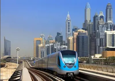 a blue train on the tracks in front of a city at Walk to JBR Marina Beach & Tram! Luxury Family 3BD, Stunning Views in Dubai