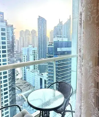 a table and chairs on a balcony with a view of a city at MARINA VIEWs STUDIO APARTMENT in Dubai
