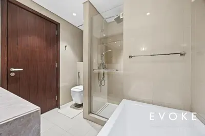 a bathroom with a shower and a toilet and a glass door at Luxury 2BR by Evoke Burj & fountain View w Sofa bed & Balcony in Dubai
