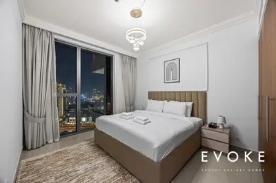 a bedroom with a large bed and a large window at Luxury 2BR by Evoke Burj & fountain View w Sofa bed & Balcony in Dubai