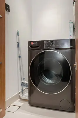 a black washing machine in a room with a broom at Inviting 1BR Apartment in JVC in Dubai
