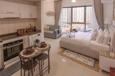 a kitchen and living room with a bed and a table at Stylish Studio Apartment with a Balcony Offering Sophistication, Spectacular Views & Beachside Living! in Dubai