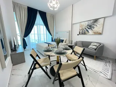a living room with a table and chairs and a couch at Cosy Studio in Opalz by Danube, Al Barsha South in Dubai