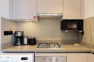 a kitchen with a stove and a microwave at Cosy 1BR in Sobha Hartland in Dubai
